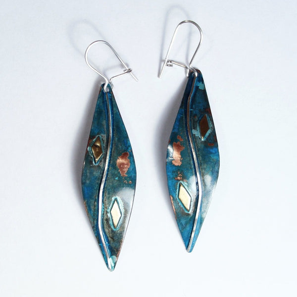 large long leaf shaped copper earrings with blue patina, little pieces of brass and a silver wire down the middle of the earring.