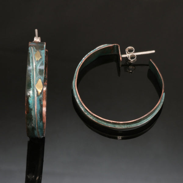 narrow copper hoops with a line of silver wire, brass accents and blue/green patina one laying on its side to show the stud