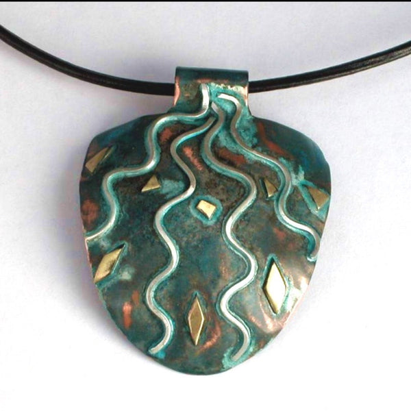 half round copper pendant with silver rays streaming down, blue/green patina and brass accents