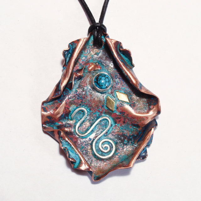 copper pendant with silver spiral, brass accents and turquoise cab on a leather band.