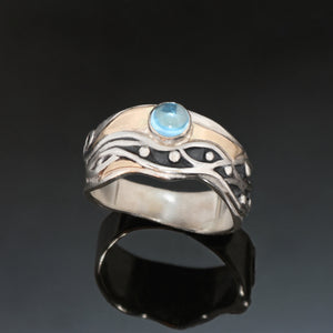 silver ring with 14k gold around silver waves oxidized black patina with blue topaz cabochon