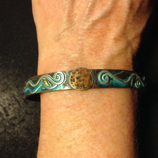 wide copper bracelet with silver spirals and hammered brass disc in the middle with green patina