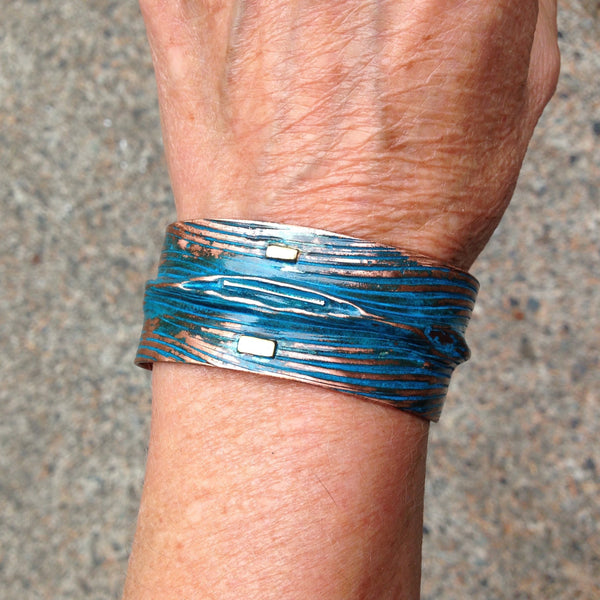wide folded copper bracelet with embossed wave pattern, blue-green patina, silver and brass accents.