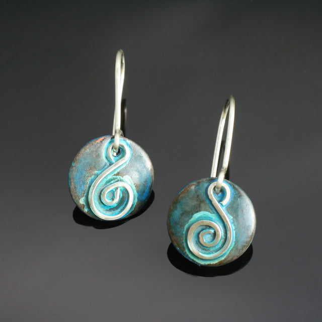 round copper earrings with silver spiral shaped like a treble clef and blue patina