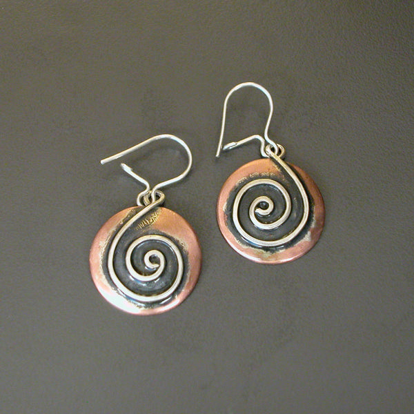 round copper earrings with silver spiral shaped like a treble clef and black patina