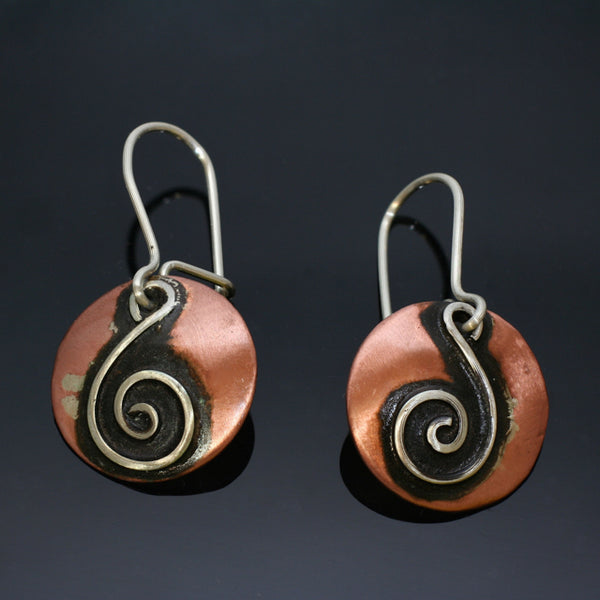 round copper earrings with silver spiral shaped like a treble clef and black patin