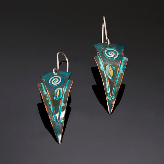 earrings with 2 copper triangles fused together with a silver spiral and brass and blue/green patina.