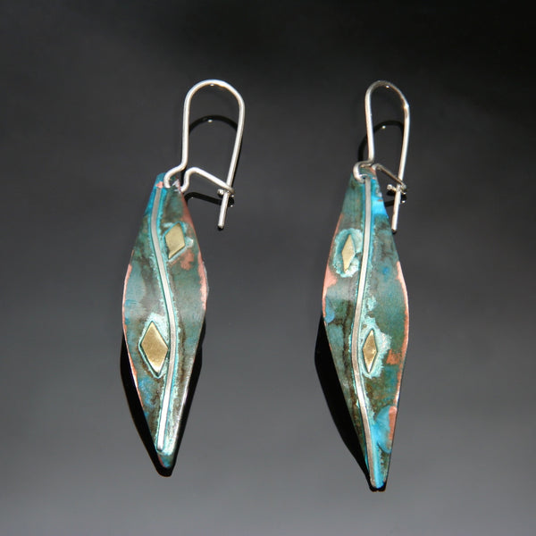 long leaf shaped copper earrings with blue/green patina, little pieces of brass and a silver wire down the middle of the earring.