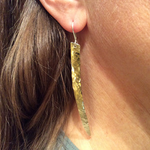 long and narrow hammered brass Earrings hanging from an earlobe