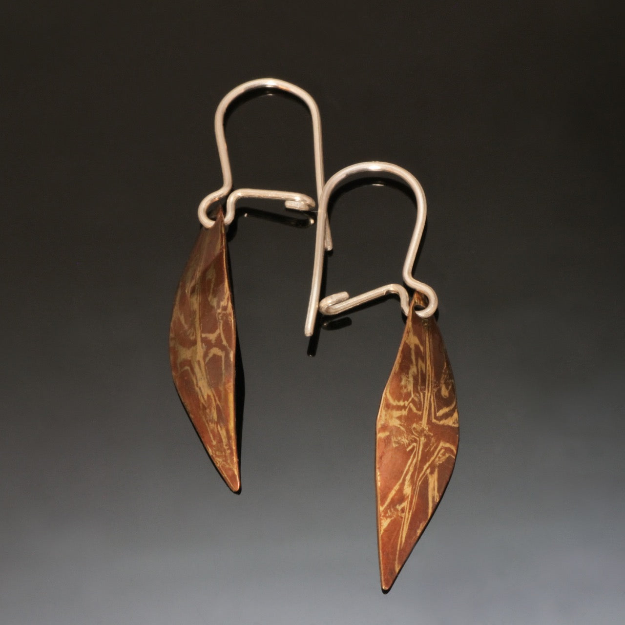 leaf shaped earrings made with copper and brass in a random pattern