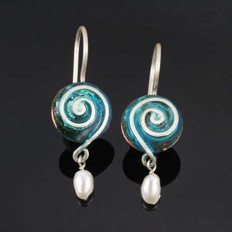 round copper earrings with blue patina and spirals ending in a pearl bead at the bottom