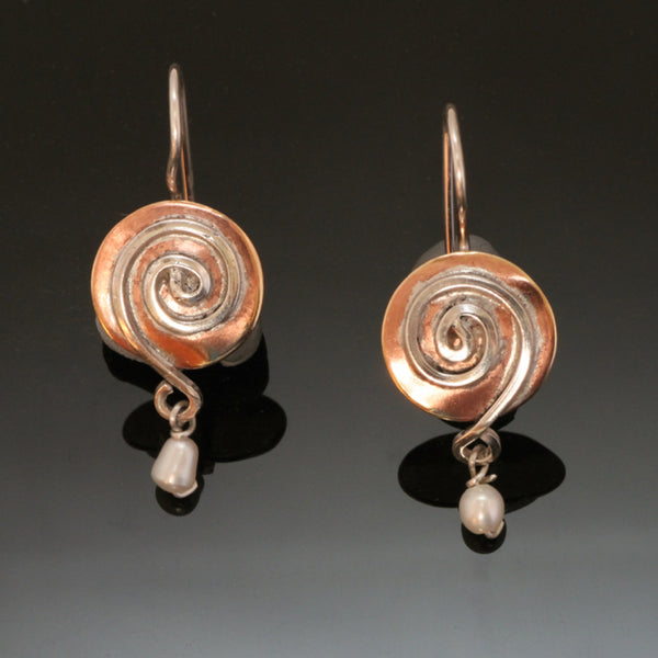 round copper earrings with spirals ending in a pearl bead at the bottom