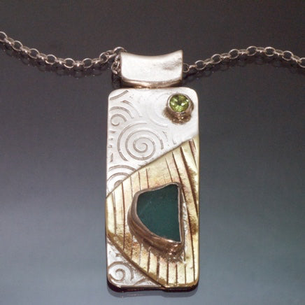 long rectangular silver brass necklace with jade coloured green beach glass and faceted peridot, spirals embossed into the silver.