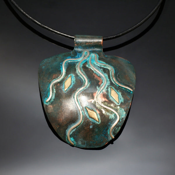 half round copper pendant with silver rays streaming down, blue/green patina and brass accents