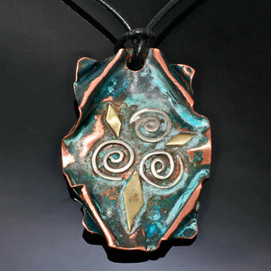 copper pendant with 3 silver spirals and brass accents on a leather band