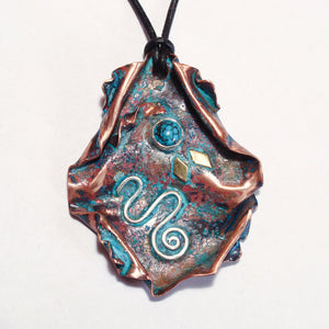 copper pendant with silver spiral, brass accents and turquoise cab on a leather band.
