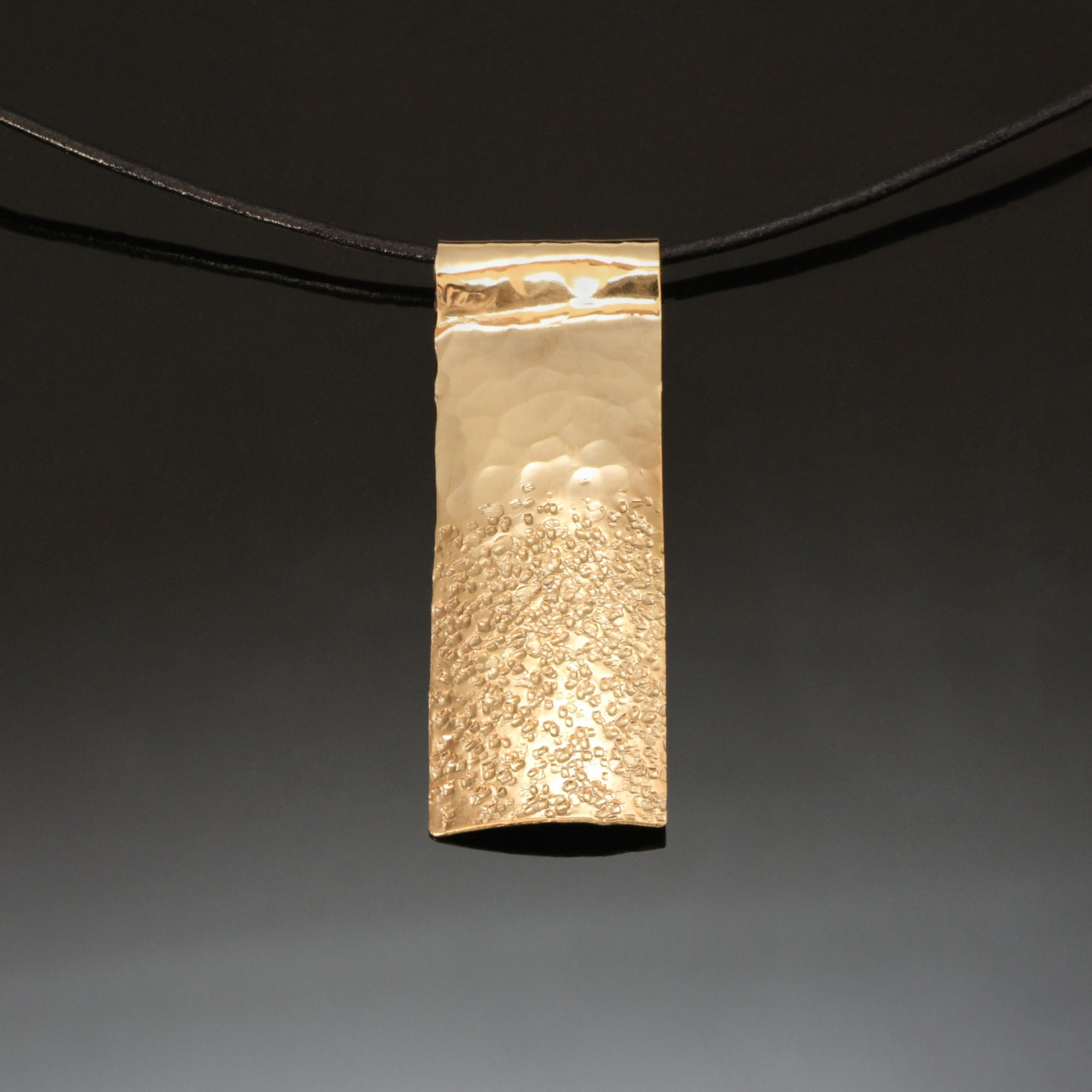 resembling sand and sky hammered brass necklace on a leather band