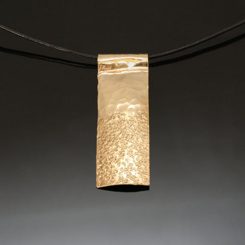 resembling sand and sky hammered brass necklace on a leather band