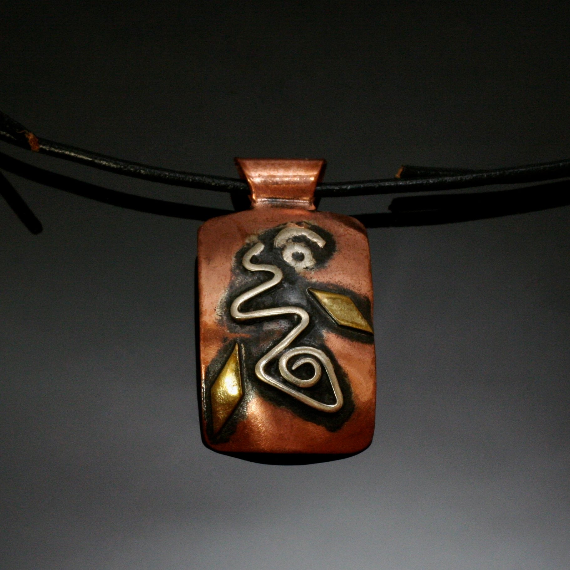 rectangular copper necklace with silver spiral, brass and black patina on a leather band