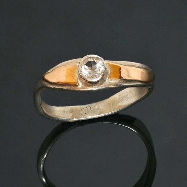 delicate wavy silver band with a wave of gold around a clear topaz.