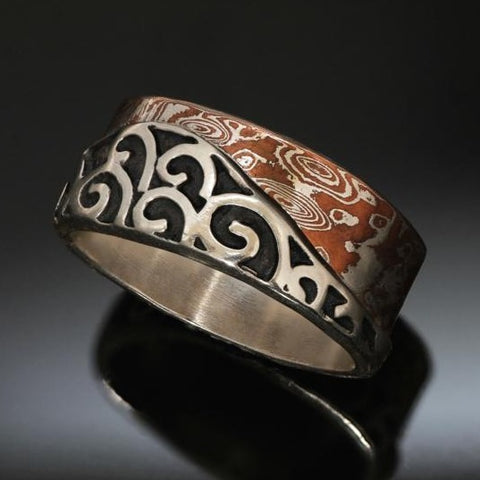 Sterling silver band made with an band of mokume gane contouring a wave of silver spirals with recessed parts oxidized black. The mokume is made with copper and silver.