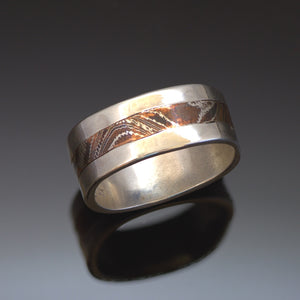 10mm wide Silver band with a centre band of mokume gane. The mokume has a wavy wood grain pattern and is made with copper and silver.