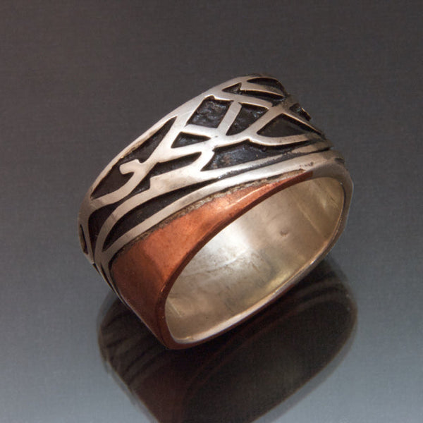 Sterling silver band made with a wavy band of copper contouring waves of sterling silver with recessed parts oxidized black.  