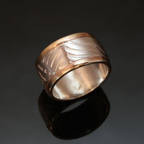 wide silver ring with fern pattern embossed and gold rails on the outside edges of the band