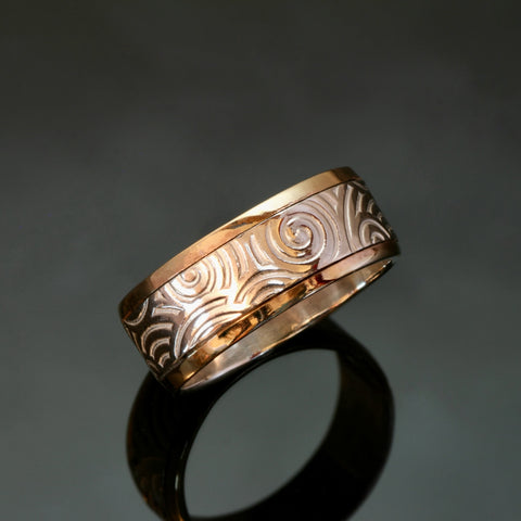silver ring with spirals embossed and gold rails on the outside edges of the band