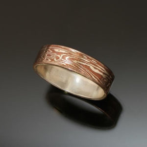 Silver band with mokume gane on the outside. The mokume has a wood grain pattern and is made with copper and silver.  