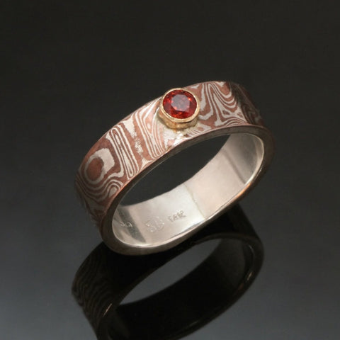 mokume ring with sterling silver, a faceted garnet set into gold bezel.