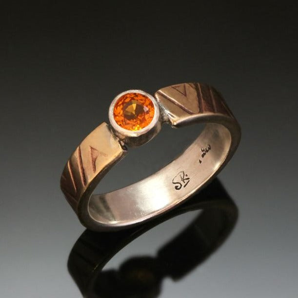 4mm wide silver ring with layer of gold tone brass embossed with zigzag pattern and orange sapphire.