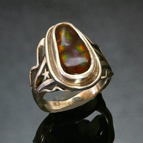 silver ring with irregular shaped fire agate set into a bezel setting. The ring widens towards the stone with lines of silver waves and a star on either side of the fire agate. 