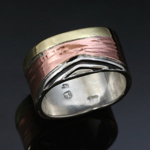 11mm Sterling silver band made with a narrow brass band beside a slightly hammered copper band beside a triangle silver wave with recessed parts oxidized black.