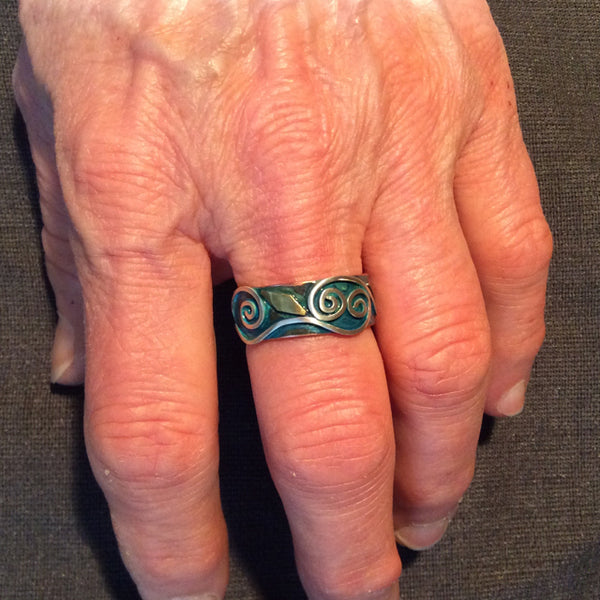 hand with copper ring with silver spirals and brass accents blue patina