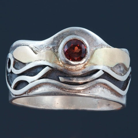silver ring with garnet surrounded by gold accents and recessed parts oxidized