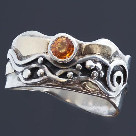 silver ring with gold accents and black patina in the wavy silver pattern with orange sapphire.