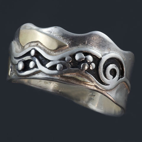 Silver ring with uneven edges, waves, spiral and dots showing a lively water scene. The oxidized pattern has gold accents around it.