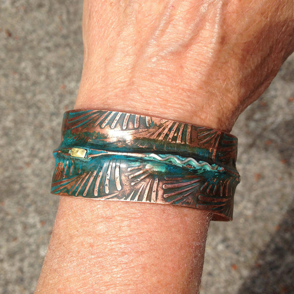 wide folded copper bracelet with blue-green patina and embossed fern pattern. Sterling silver waves and brass accents.