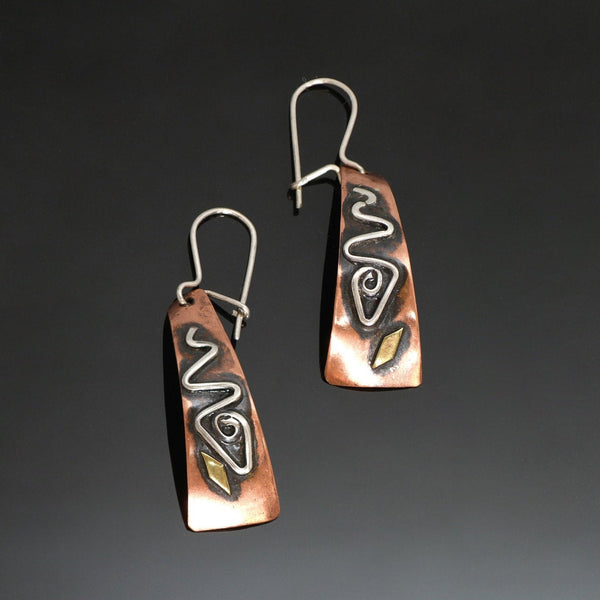 long copper earrings with a spiral fish design, brass and black patina