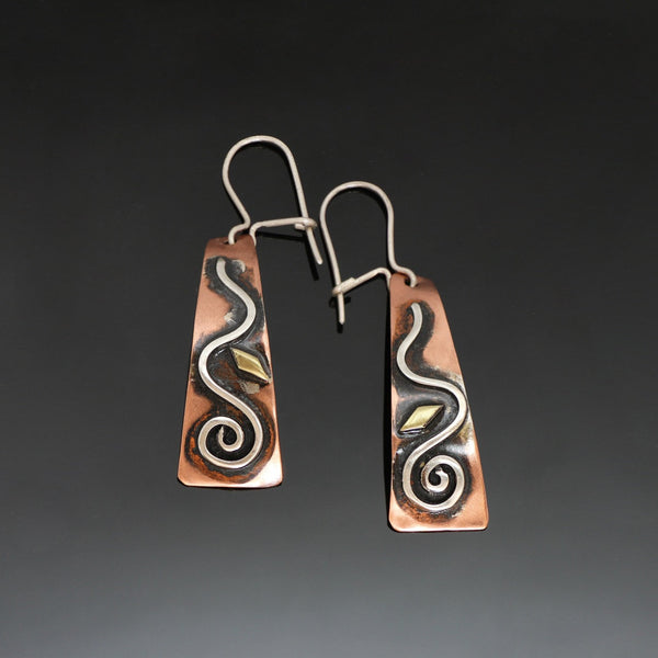 long copper earrings with a silver spiral wave, brass and black patina