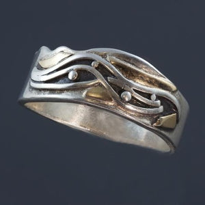 Silver ring with raised wave and dots which is oxidized black and gold accents around the pattern.